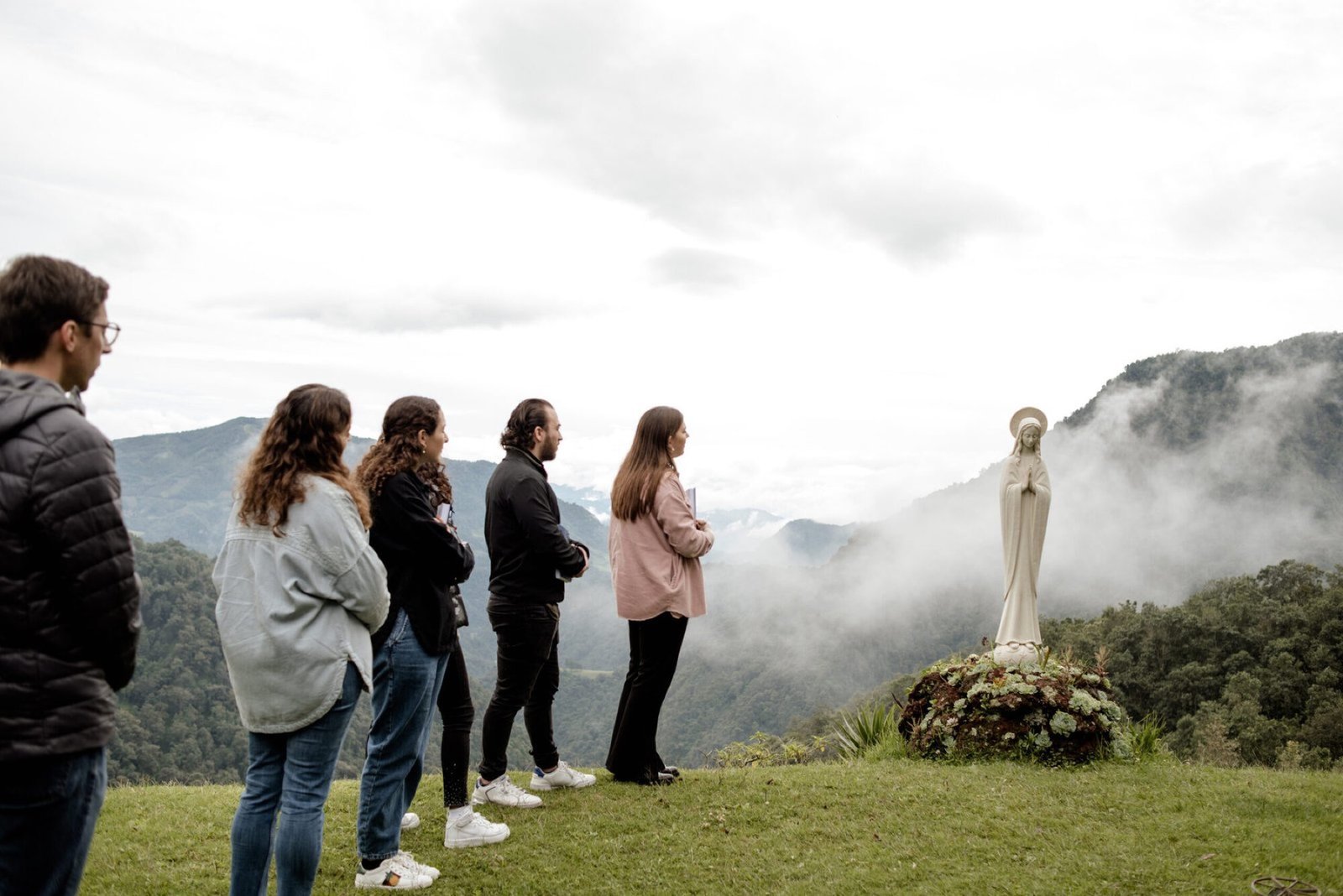 Jóvenes en oración frente a una imagen de la Virgen, en la montaña